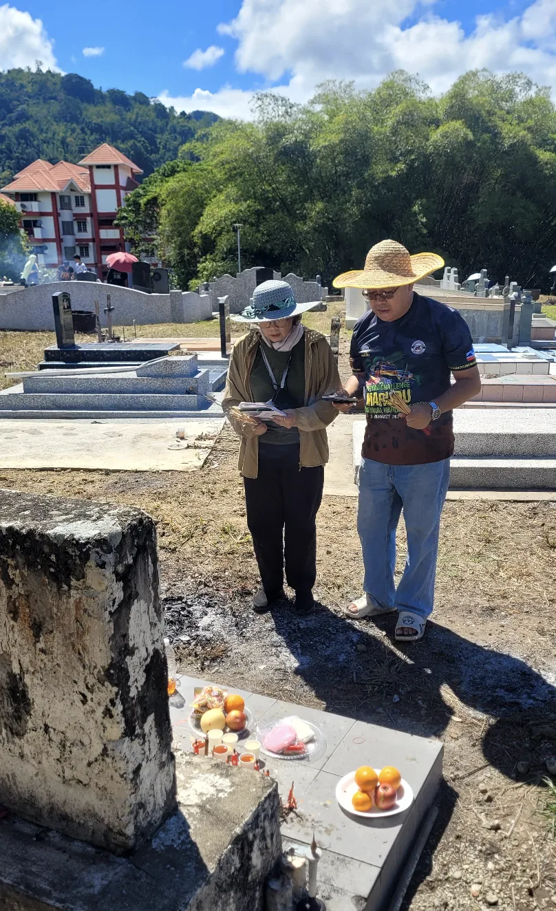 Mum and a relative at the first grave with offerings